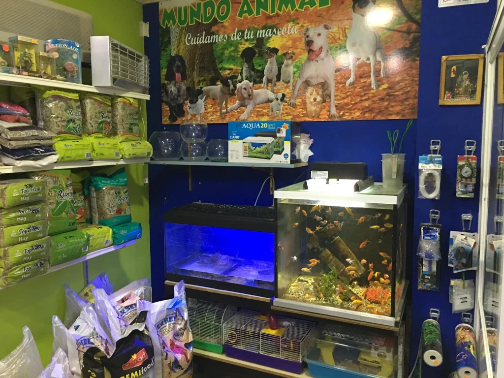 Vista interior de tienda de alimentación y accesorios para mascotas en Atarfe, con productos variados, acuarios y jaulas